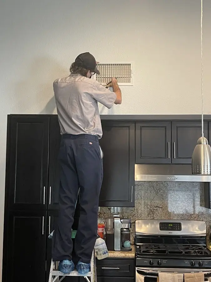 Technician inspecting an air vent during HVAC service in Mantua